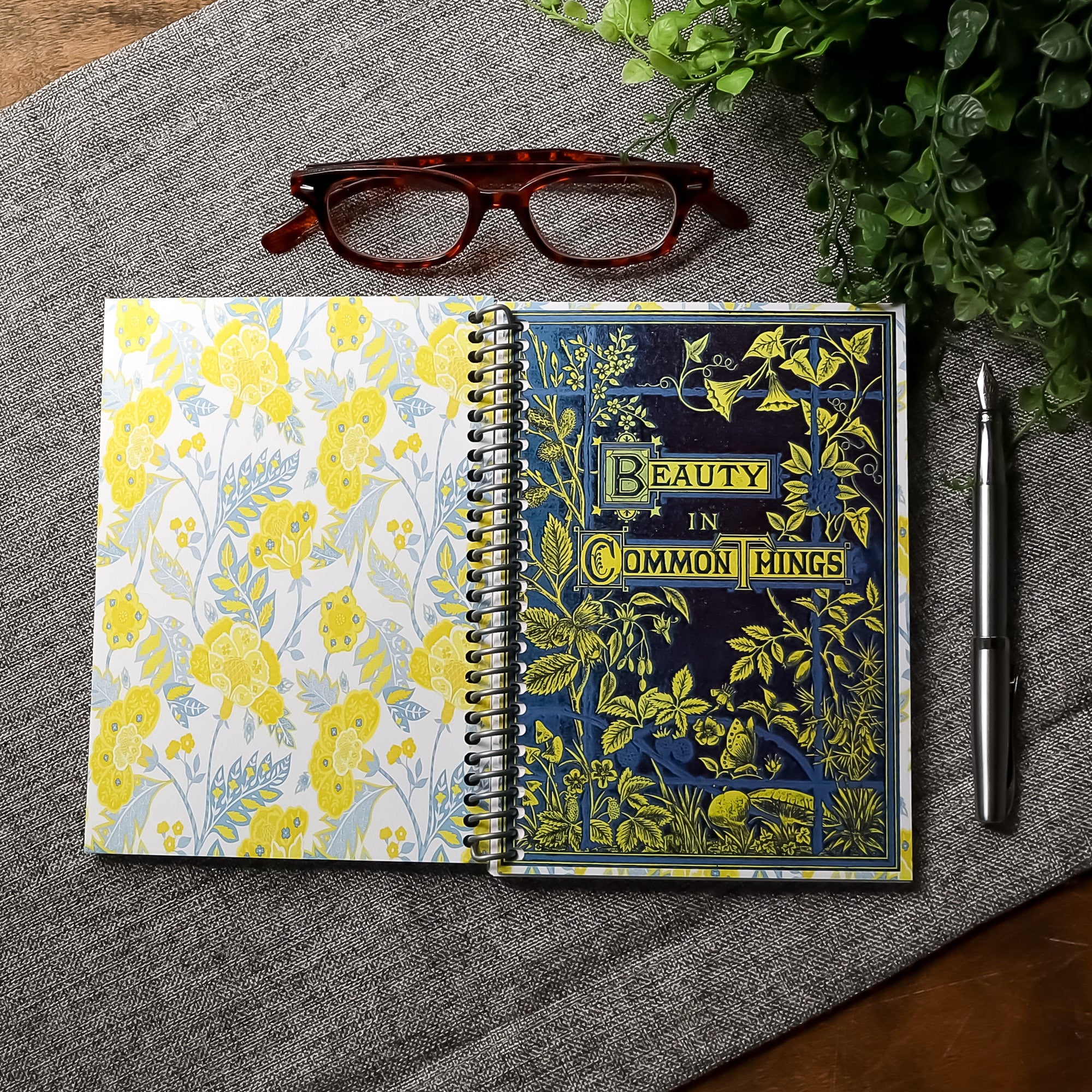 handmade travel notebook (5&quot; x 7&quot;) featuring a vintage book cover, Beauty in Common Things. Colors: navy blue, yellow, white, and light blue. Floral Patterns.