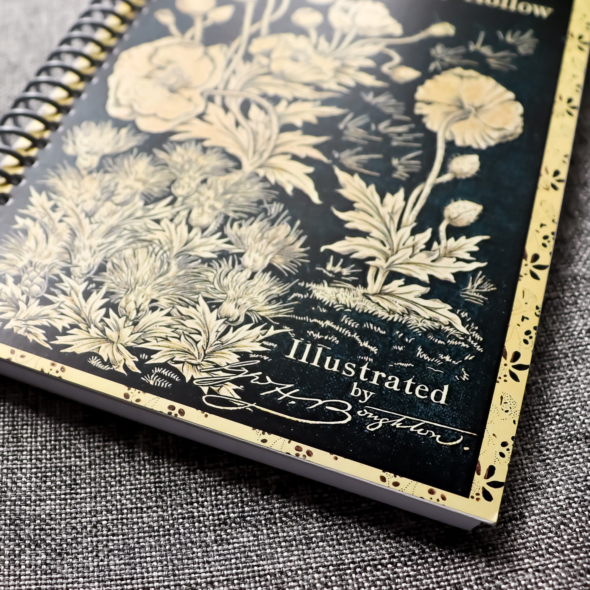 A travel-sized spiral notebook featuring a vintage book cover: Rip Van Winkle and The Legend of Sleepy Hollow by Washington Irving. Features a bold floral design. The colors are black and gold.