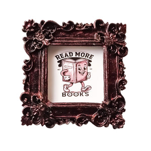 This is a small framed refrigerator magnet, featuring the phrase &quot;Read More Books&quot;, made by SunshineandRavioli. The resin frame is ornate vintage style in a metallic burgundy finish. A retro style illustration features a whimsical walking book giving a &quot;thumbs up&quot;.